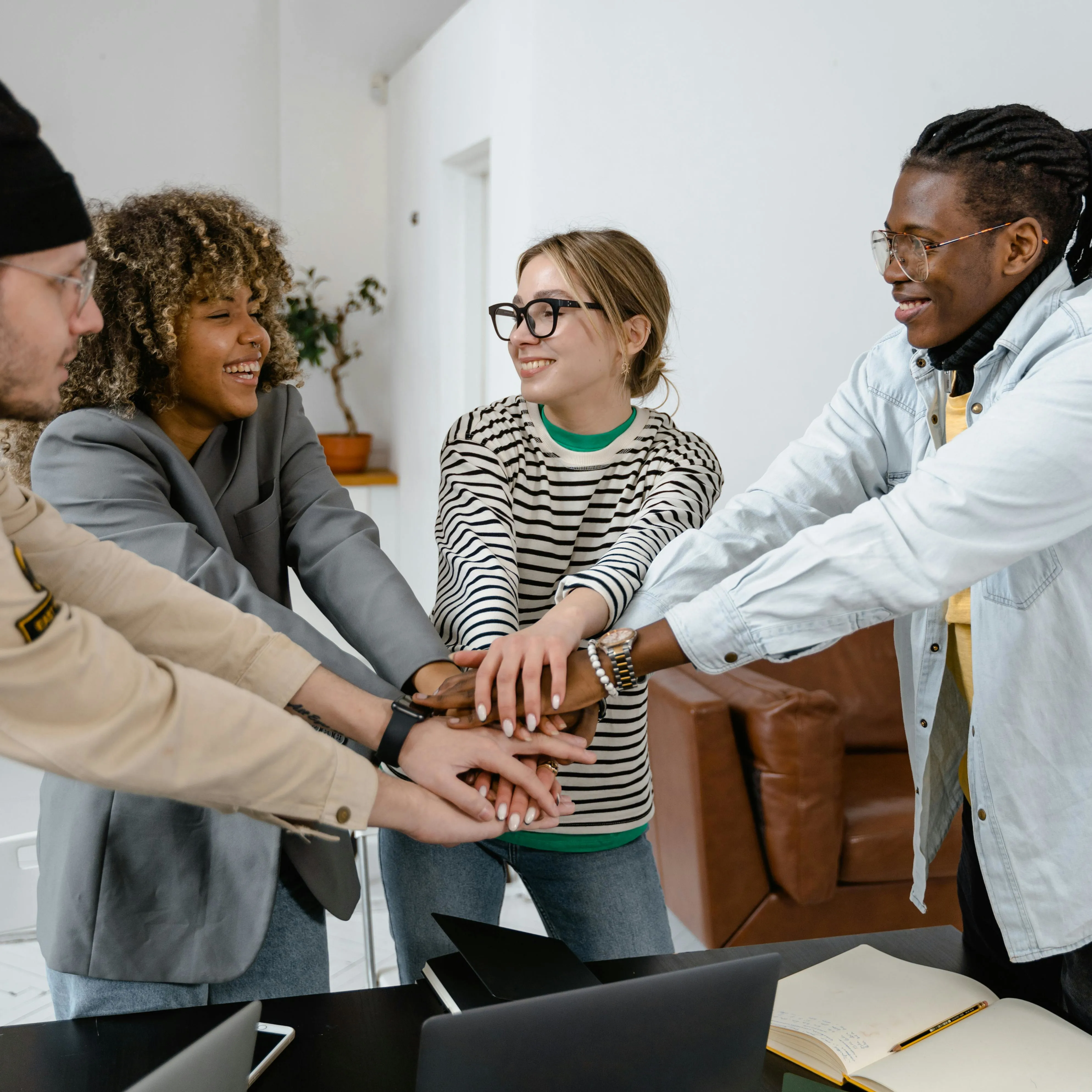 A group of people putting their hands together in support of each other and smiling
